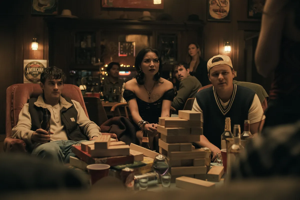 Obsession 2025 film sahnesi: Bear, Nikki ve diger karakterler bar ve oyun ortaminda, filminin atmosferini yansitan resmi sahne