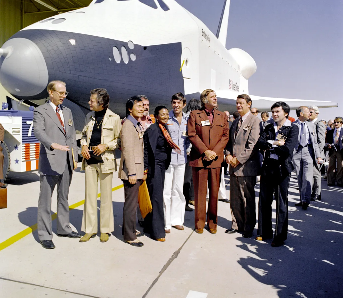 Gene Roddenberry ve orijinal Star Trek dizisi oyuncu kadrosu (Leonard Nimoy, Nichelle Nichols, George Takei, DeForest Kelley, James Doohan, Walter Koenig), 1976'da uzay mekiği Enterprise ile birlikte.