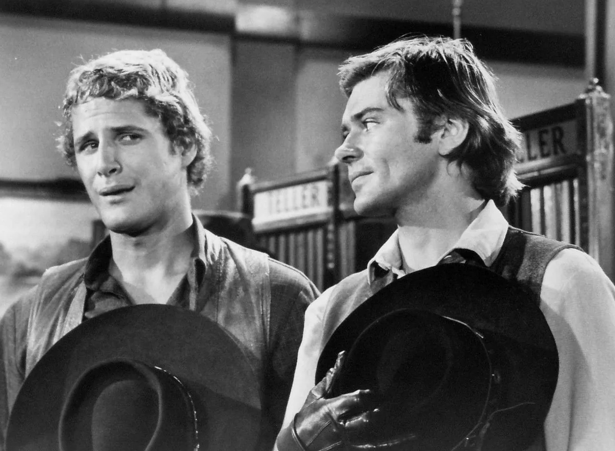 Alias Smith and Jones dizisinde Pete Duel (Hannibal Heyes) ve Ben Murphy (Kid Curry), banka gişesi önünde şapkalarıyla