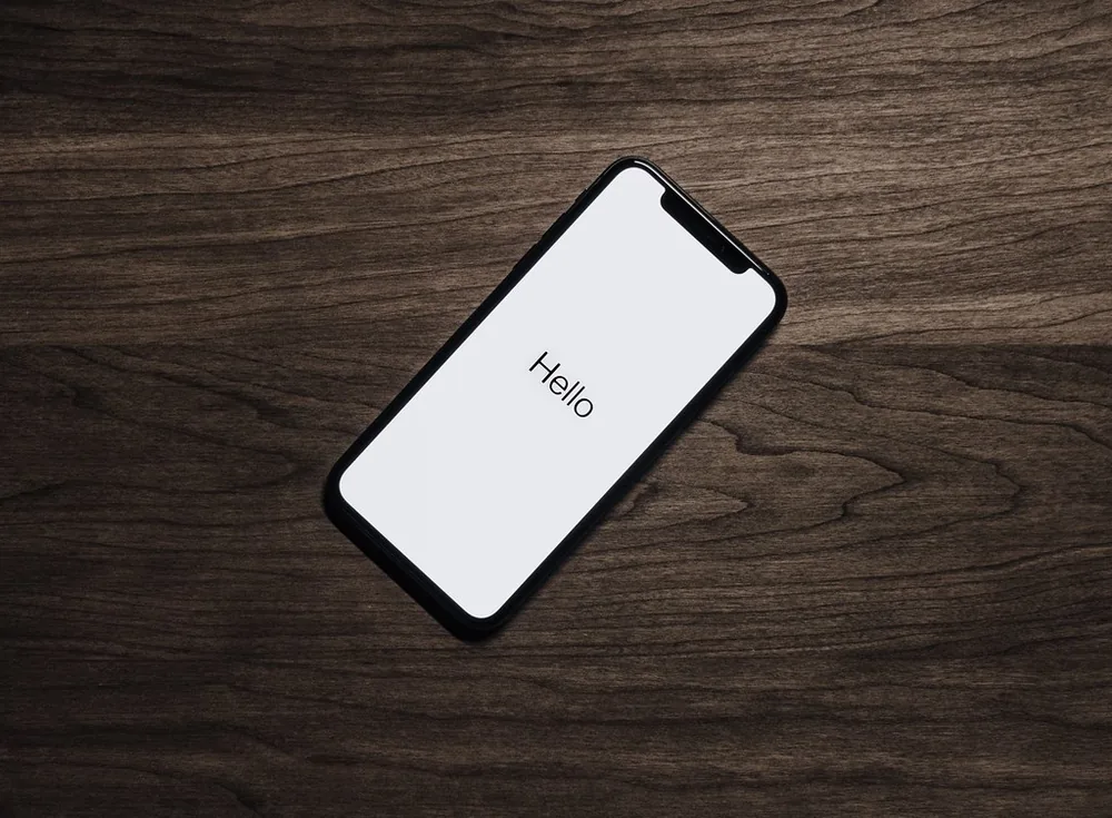 Kılıfsız bir akıllı telefon ahşap bir yüzeyde soğumaya bırakılmış; aşırı ısınan telefonu güvenle soğutma adımını gösteriyor