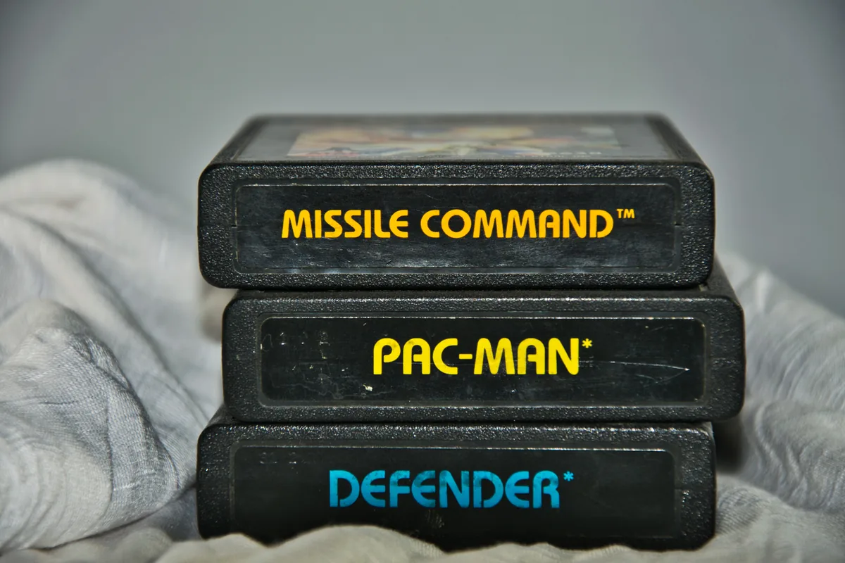 Üst üste dizilmiş klasik Atari oyun kartuşları: Missile Command, Pac-Man ve Defender
