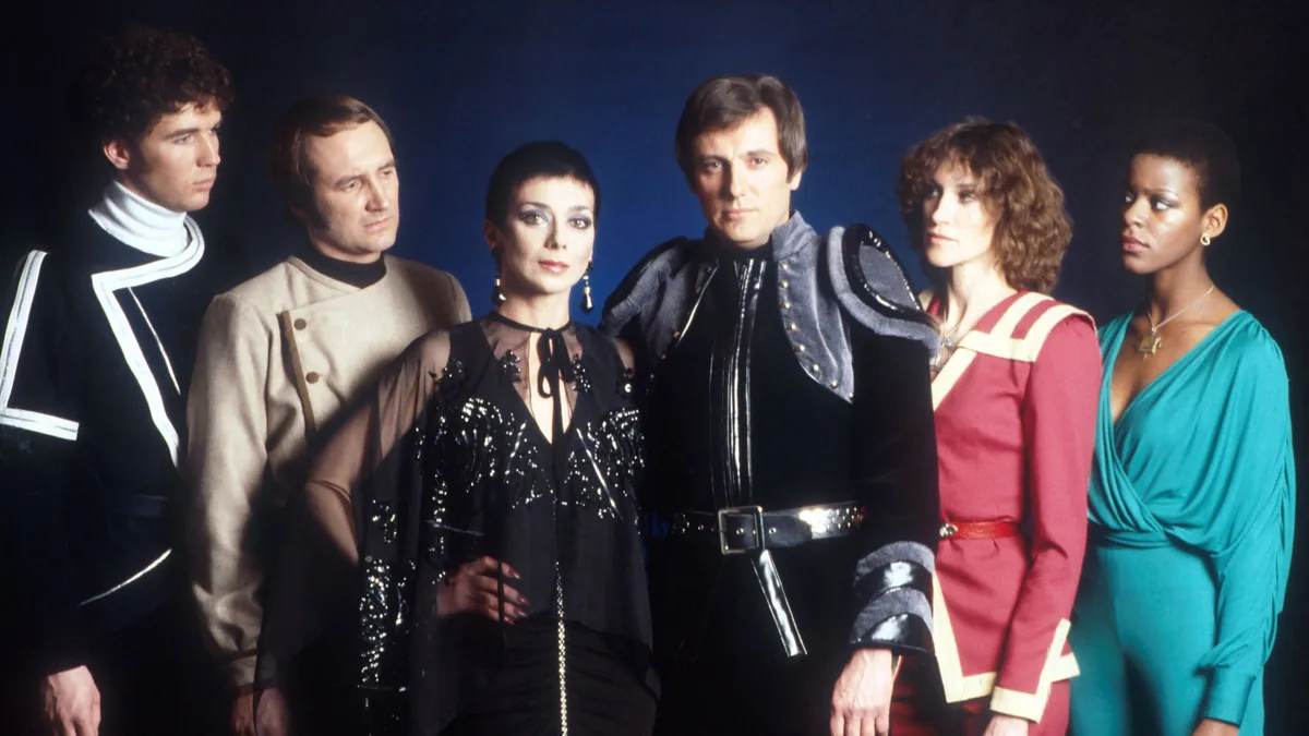 Kerr Avon (Paul Darrow) ve Federasyon komutanı Servalan (Jacqueline Pearce) Blake's 7 dizisinin resmi tanıtım fotoğrafında bir arada