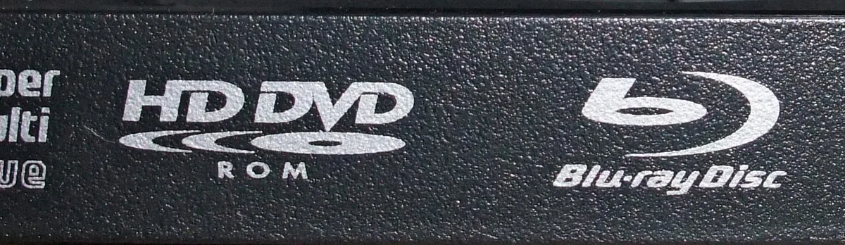 Bir optik sürücü üzerinde HD DVD-ROM ve Blu-ray Disc logolarının yakın çekimi, iki formatın teknik karşılaştırmasını simgeliyor
