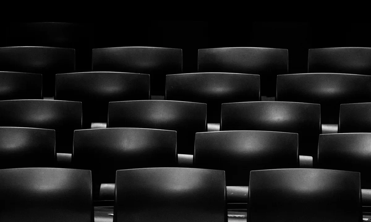 Sinema salonunda dramatik ışıklandırmayla çekilmiş boş koltuk sıraları, sinematografi ve görüntü yönetmenliği temasını simgeliyor