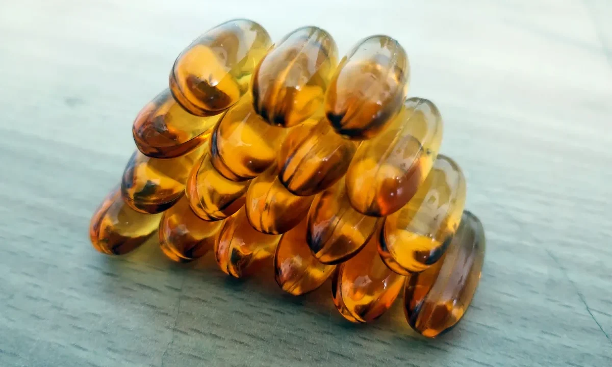 Beyaz zeminde altın rengi omega-3 balık yağı kapsülleri; beyin sağlığı için balık yağı takviyesi kavramı