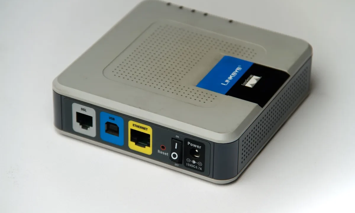 Bir modem/routerın arka panelindeki DSL, USB ve Ethernet portlarının yakın çekimi; port yönlendirme olmadan uzaktan erişim konusunu temsil eden kapak görseli