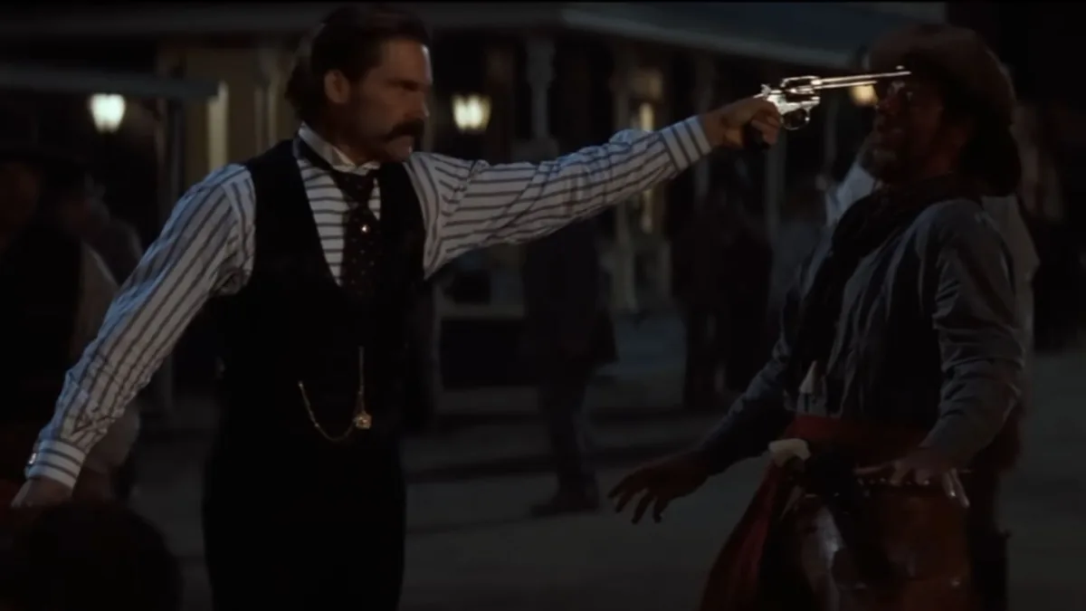 Tombstone filminde bir karakterin silahını bir çeteciye doğrultarak gerilimli bir çatışma anını canlandırdığı sahne