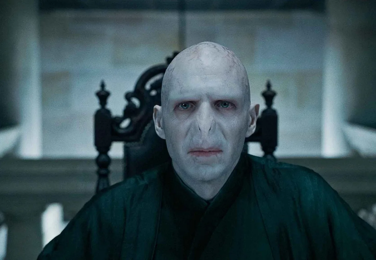 Lord Voldemort'un yılan yüzü ve asasıyla karanlık bir salonda resmi film görüntüsü