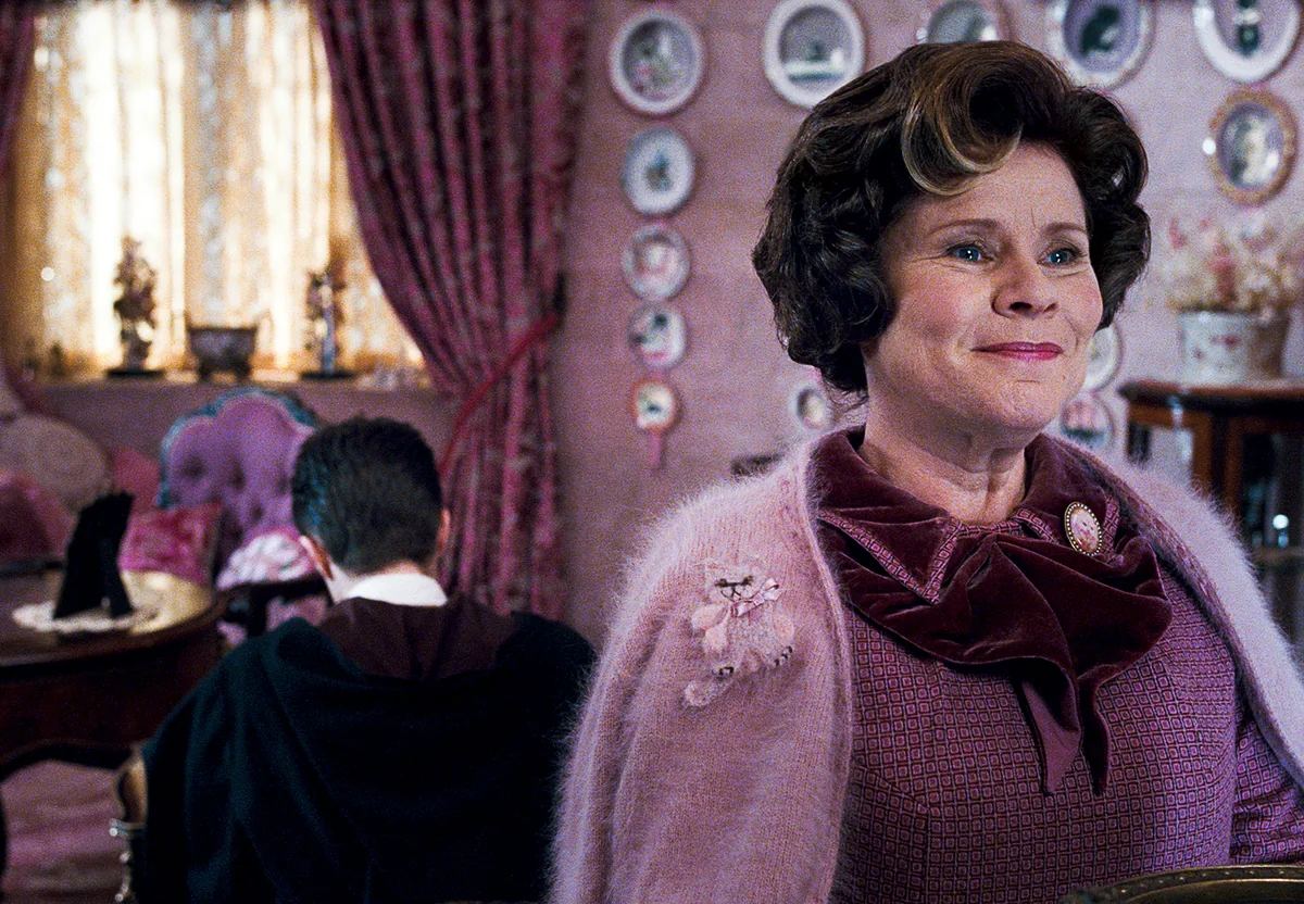 Dolores Umbridge'in pembe takım elbisesi ve sahte gülümsemesiyle ofisinde resmi film görüntüsü