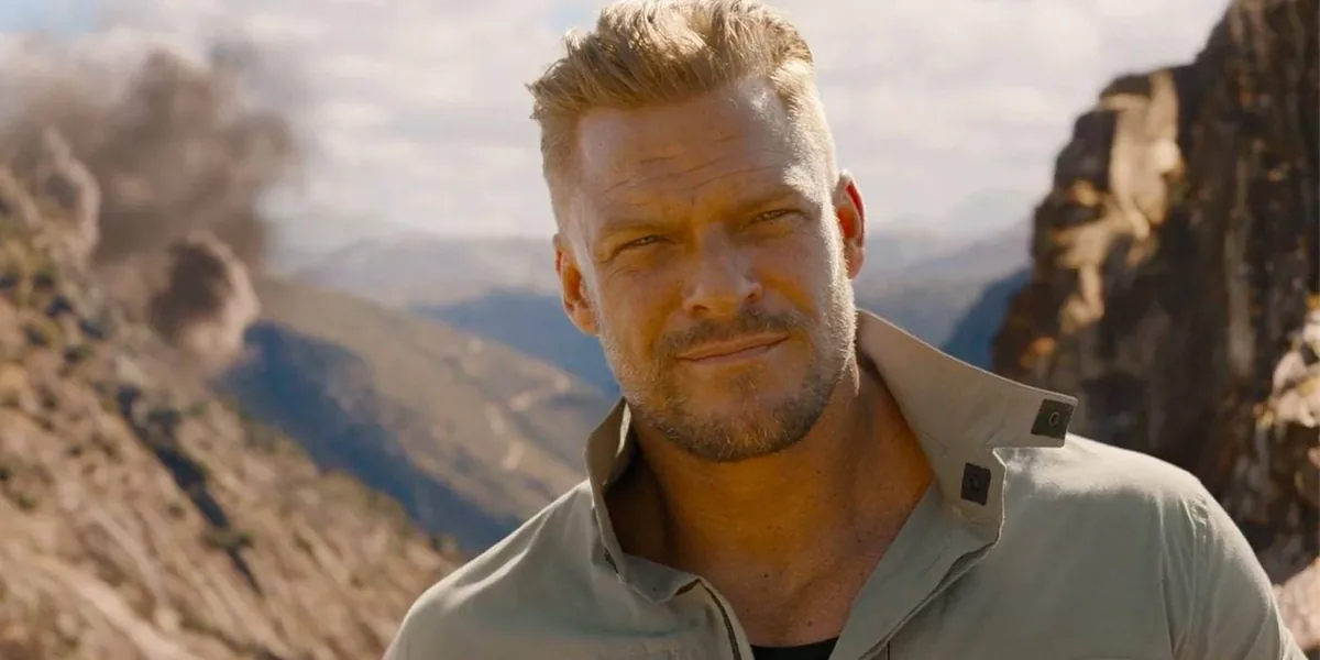 Alan Ritchson, Fast X filminde Ajan Aimes rolünde dağlık arazi manzarası önünde